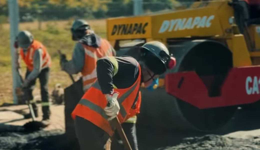 Equipe da CJ Asfaltos aplicando asfalto em campo, com rolo compactador